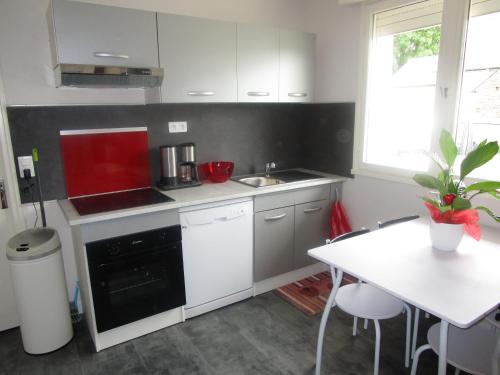 une cuisine avec des armoires blanches et une table blanche dans l'établissement Maison proche Mont St Michel et St Malo, à Roz-sur-Couesnon