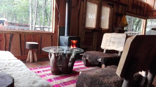 a living room with a fireplace and a table and chairs at Cabañas Rústicas Pucón Río Trancura in Pucón