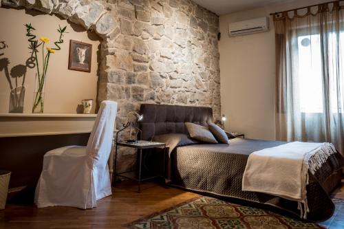- une chambre avec un lit et un mur en pierre dans l'établissement Palazzo Cosentino, à Caltanissetta