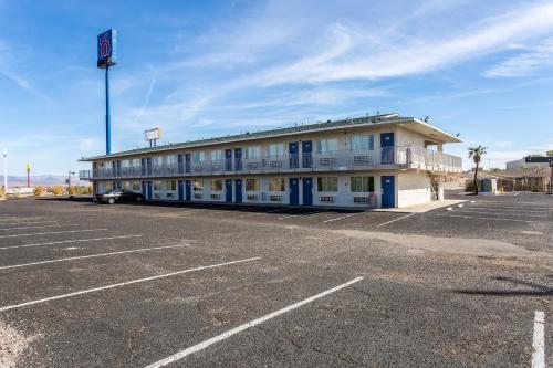 a white building with blue windows and a parking lot at Motel 6-Needles, CA in Needles