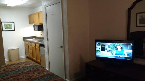 a bedroom with a television on a dresser with a kitchen at Affordable Suites Charlottesville in Charlottesville