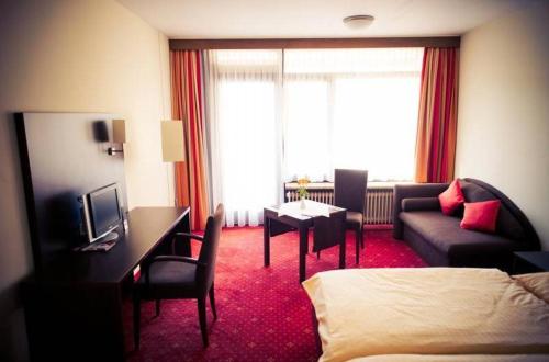 una camera d'albergo con letto, divano e scrivania di Hotel Restaurant Sonne-Post a Murrhardt