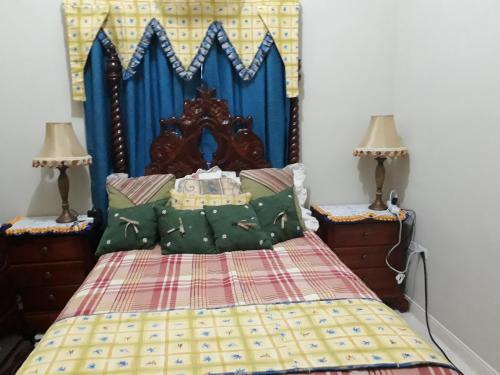 a bedroom with a bed with a blue headboard and two lamps at Jacaranda Homes in Spanish Town