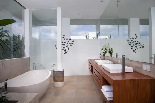 a bathroom with two sinks and a tub and a bath tub at The Palm House in Canggu
