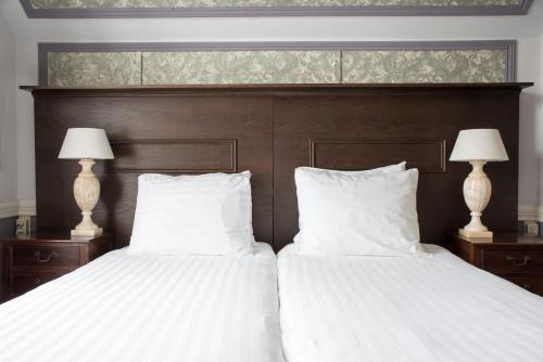 two white beds with white pillows and two lamps at Hotel Fidder - Patrick's Whisky Bar in Zwolle