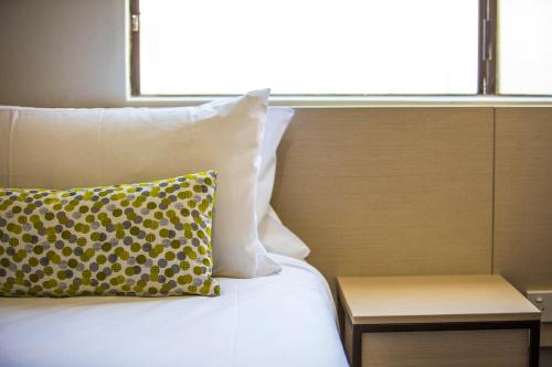 a bed with a yellow pillow next to a window at Nightcap at Blue Cattle Dog Hotel in St Marys