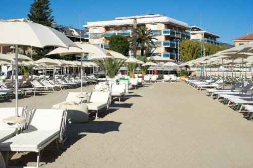 a row of lounge chairs and umbrellas on a beach at Hotel Garden Lido in Loano