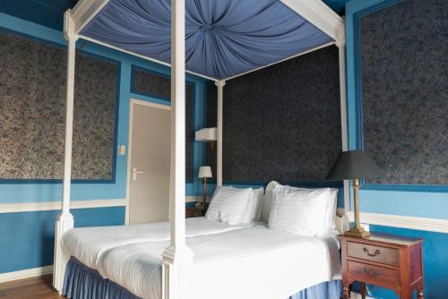 a bedroom with a canopy bed with blue walls at Hotel Fidder - Patrick's Whisky Bar in Zwolle