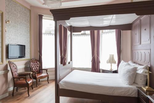 a bedroom with a canopy bed and a tv at Hotel Fidder - Patrick's Whisky Bar in Zwolle