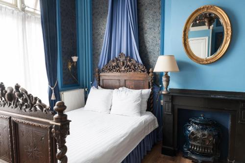 a bedroom with a bed with blue walls and a mirror at Hotel Fidder - Patrick's Whisky Bar in Zwolle