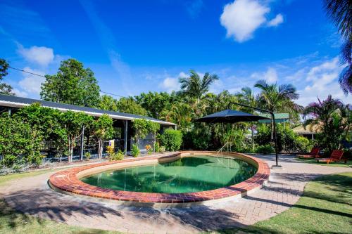 a swimming pool in a yard with an umbrella at Tasman Holiday Parks - Hervey Bay in Hervey Bay