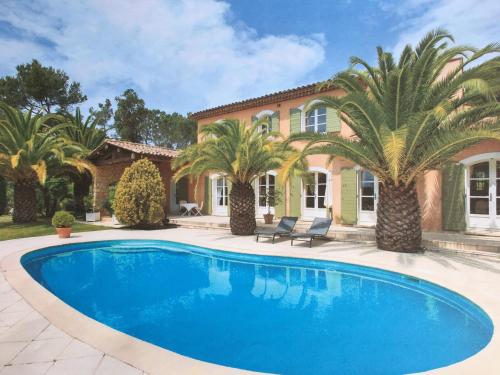 une piscine devant une maison avec des palmiers dans l'établissement Le Champmazet, à La Roquette-sur-Siagne