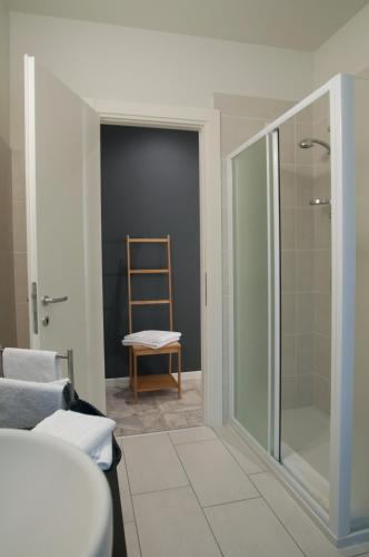 a bathroom with a glass shower and a chair at Relais Merizzi in Tirano