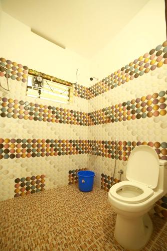 a bathroom with a toilet and a tiled wall at Arabian Nights Munnar Pool Villa in Munnar