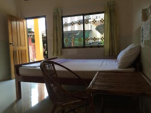 a bedroom with a bed and a chair and a window at Ta Eng Guesthouse in Kampot
