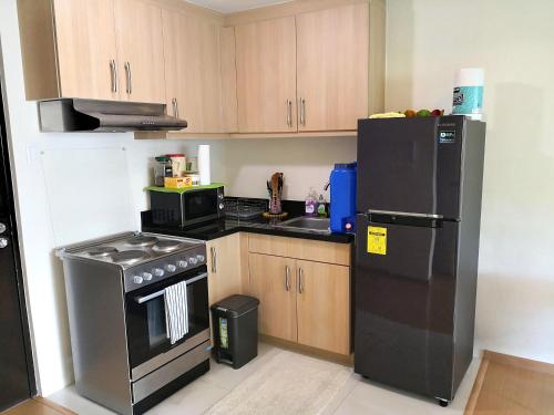 a kitchen with a black refrigerator and a stove at Avant Apartments at The Fort in Manila