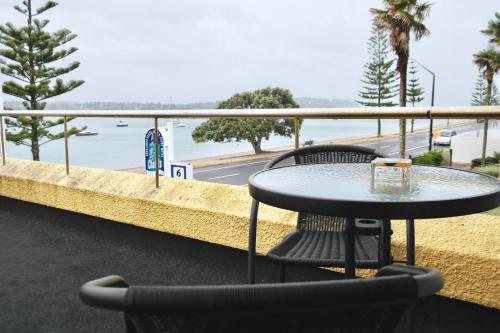 a table and chairs on a balcony with a view of the ocean at Bucklands Beach Waterfront Motel in Auckland
