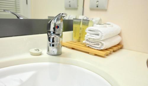 a bathroom sink with a faucet and a stack of towels at Bucklands Beach Waterfront Motel in Auckland