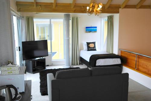 a living room with a bed and a couch at Bucklands Beach Waterfront Motel in Auckland