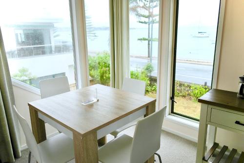 a table and chairs in a room with a large window at Bucklands Beach Waterfront Motel in Auckland