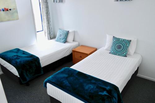 a room with two beds with blue pillows at Bucklands Beach Waterfront Motel in Auckland