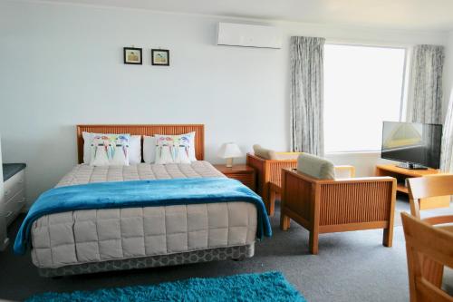 a bedroom with a large bed and a television at Bucklands Beach Waterfront Motel in Auckland