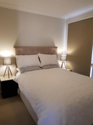 ein Schlafzimmer mit einem großen weißen Bett mit zwei Lampen in der Unterkunft Blue on McNab in Katoomba