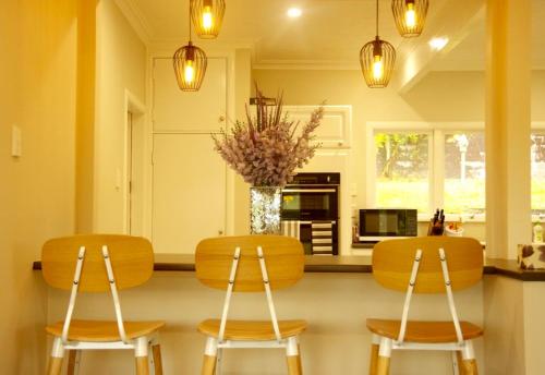 a kitchen with two chairs and a table with a vase at Lake Domain Boarding Holiday House in Hamilton