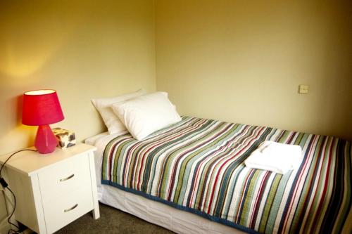 a bedroom with a bed with a red lamp on a night stand at Lake Domain Boarding Holiday House in Hamilton