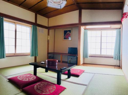 a living room with a table and two windows at Yamakyuso in Otari