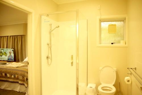 a bathroom with a shower and a toilet and a bed at Lake Domain Boarding Holiday House in Hamilton