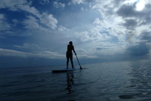 a man standing on a paddle board in the water at Bella Nilaveli Beach in Nilaveli