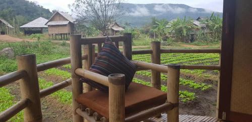 a bench with a pillow sitting on top of a fence at Namkat Yorla Pa Resort in Ban Kat