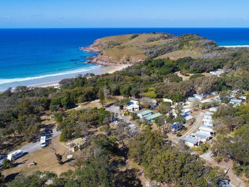 an aerial view of a beach with houses and the ocean at Grassy Head Holiday Park in Stuarts Point