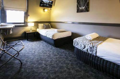 a bed room with two beds and a desk at Imperial Hotel Maitland in Maitland