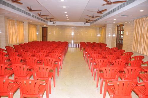 a room filled with red chairs in a building at Raya's Grand in Kumbakonam