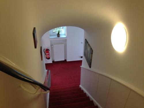 a hallway with a red carpet and stairs with a window at Hotel Destination 21 in Düsseldorf