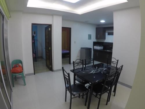 a dining room with a black table and chairs at Penthouse Apartment in Dagupan in Dagupan