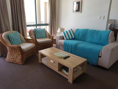a living room with a couch and two chairs and a coffee table at Excellsior Apartments in Mooloolaba