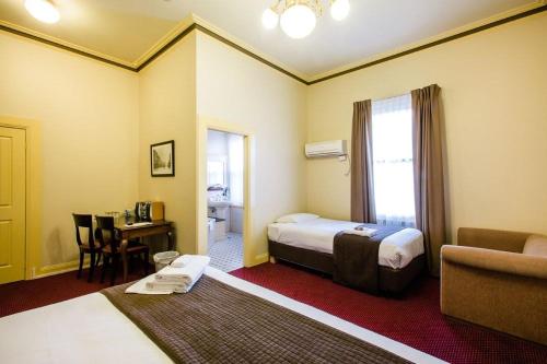 a bedroom with a bed and a table and a couch at The Glenferrie Hotel Hawthorn in Melbourne