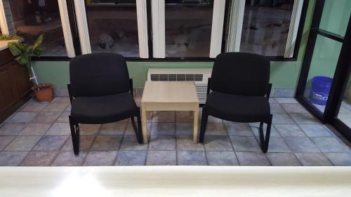 2 sillas negras y una mesa en el balcón en Mentor Home Inn and Suites en Mentor