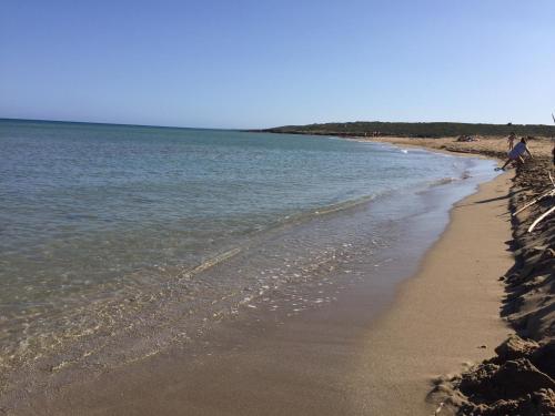 a beach with people walking on the sand and water at I Carusi Relais in Noto