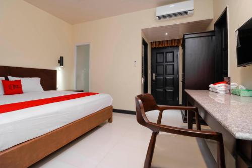 a bedroom with a bed and a desk with a chair at RedDoorz Plus near Halim Perdanakusuma 2 in Jakarta