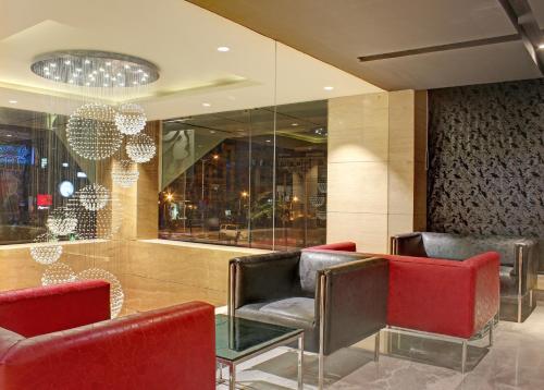 a lobby with red chairs and a glass table at Ramada Encore Domlur Bangalore in Bengaluru