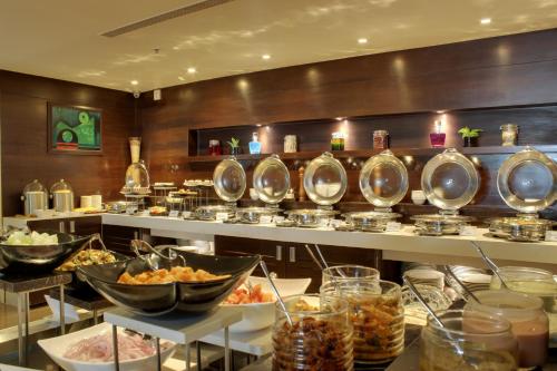 a buffet line with bowls of food in a restaurant at Ramada Encore Domlur Bangalore in Bengaluru