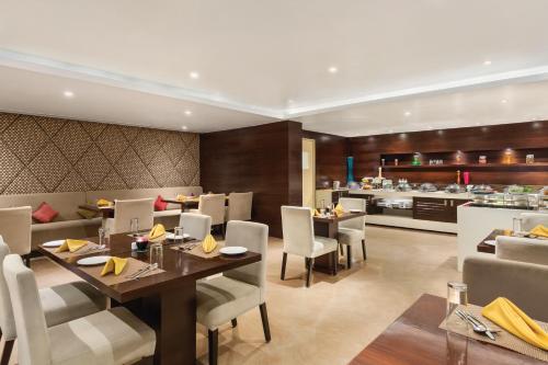 a restaurant with tables and chairs and a kitchen at Ramada Encore Domlur Bangalore in Bengaluru