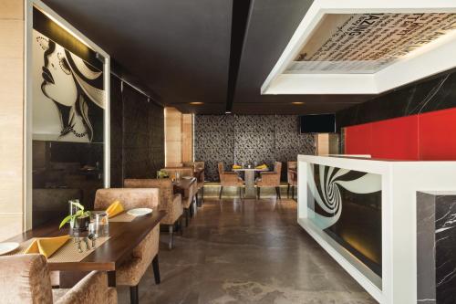 a restaurant with wooden tables and chairs and a red wall at Ramada Encore Domlur Bangalore in Bengaluru