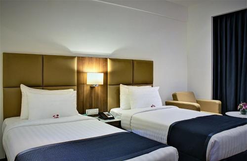 una habitación de hotel con 2 camas y una silla en Ramada Encore Domlur Bangalore, en Bangalore