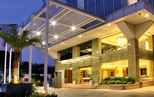 a large building with a palm tree in front of it at Ramada Encore Domlur Bangalore in Bengaluru