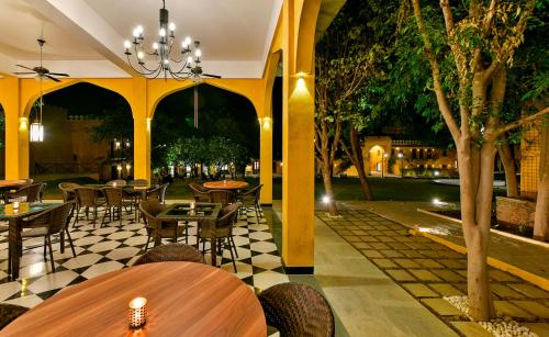 a restaurant with tables and chairs and trees at Gogunda Palace in Udaipur